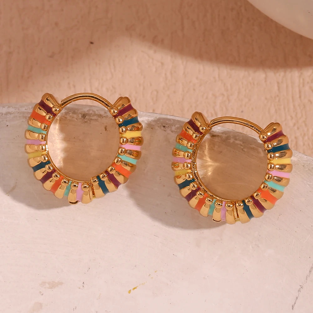 Gold hoop earrings with colorful accents on a light background