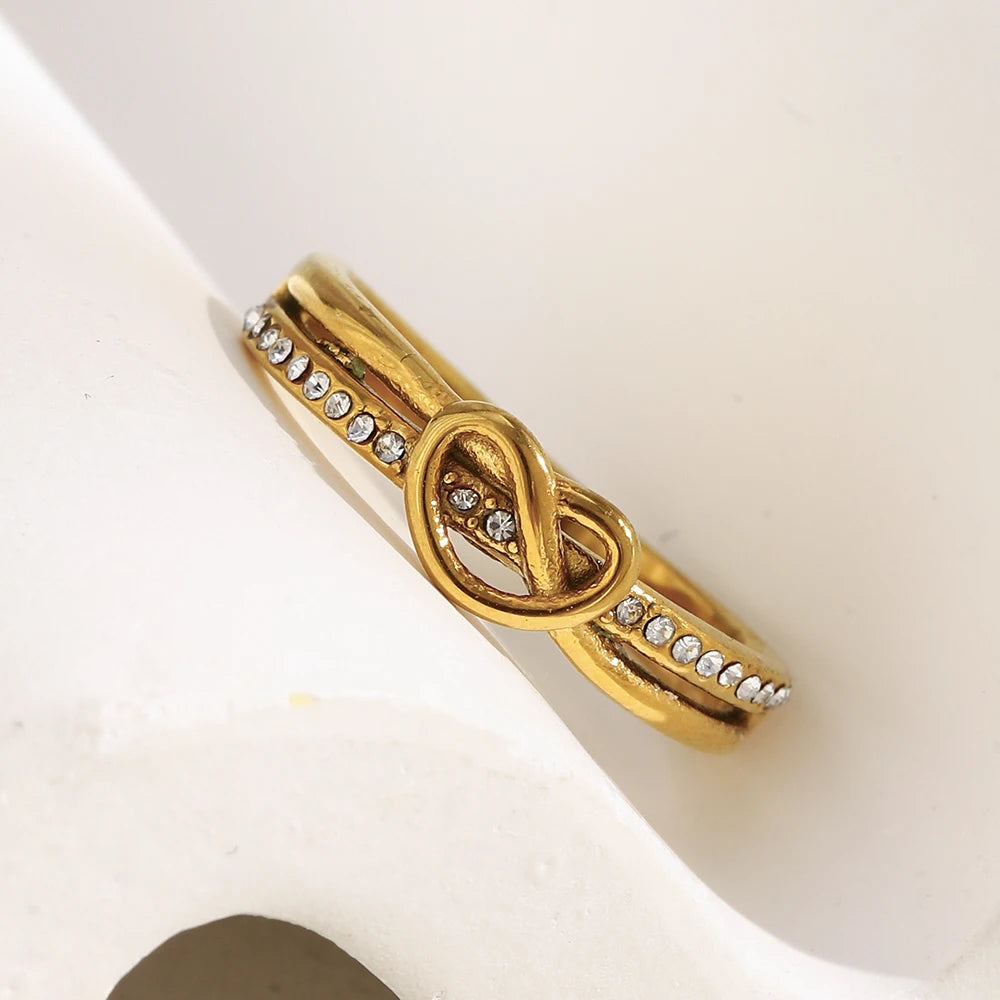 Gold bracelet with interlocking design and small stones on a white surface