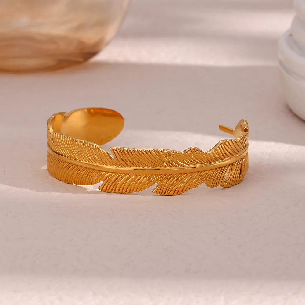 Gold feather-shaped bracelet on a light background