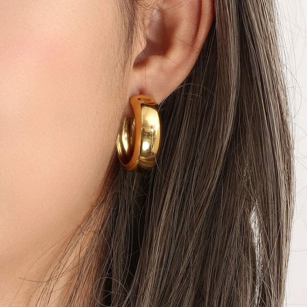 Gold hoop earring worn by a person with brown hair.