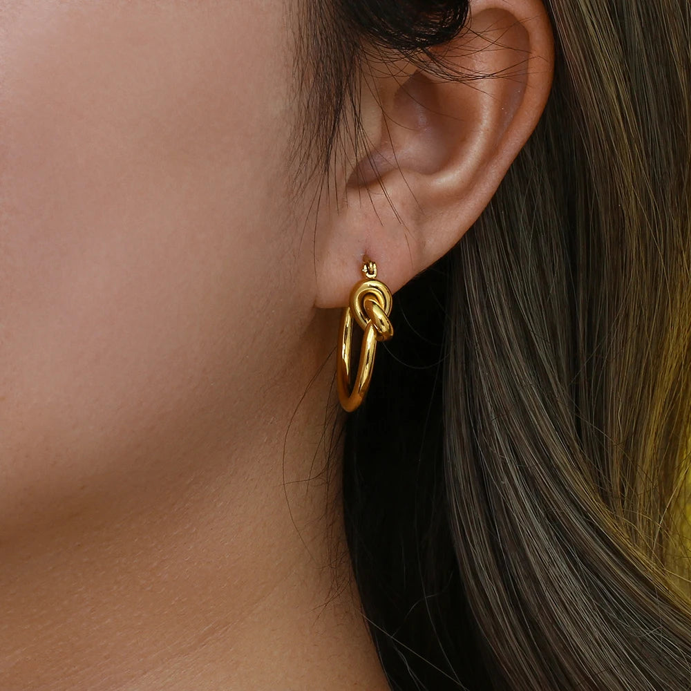 Gold hoop earring worn by a person with dark hair.