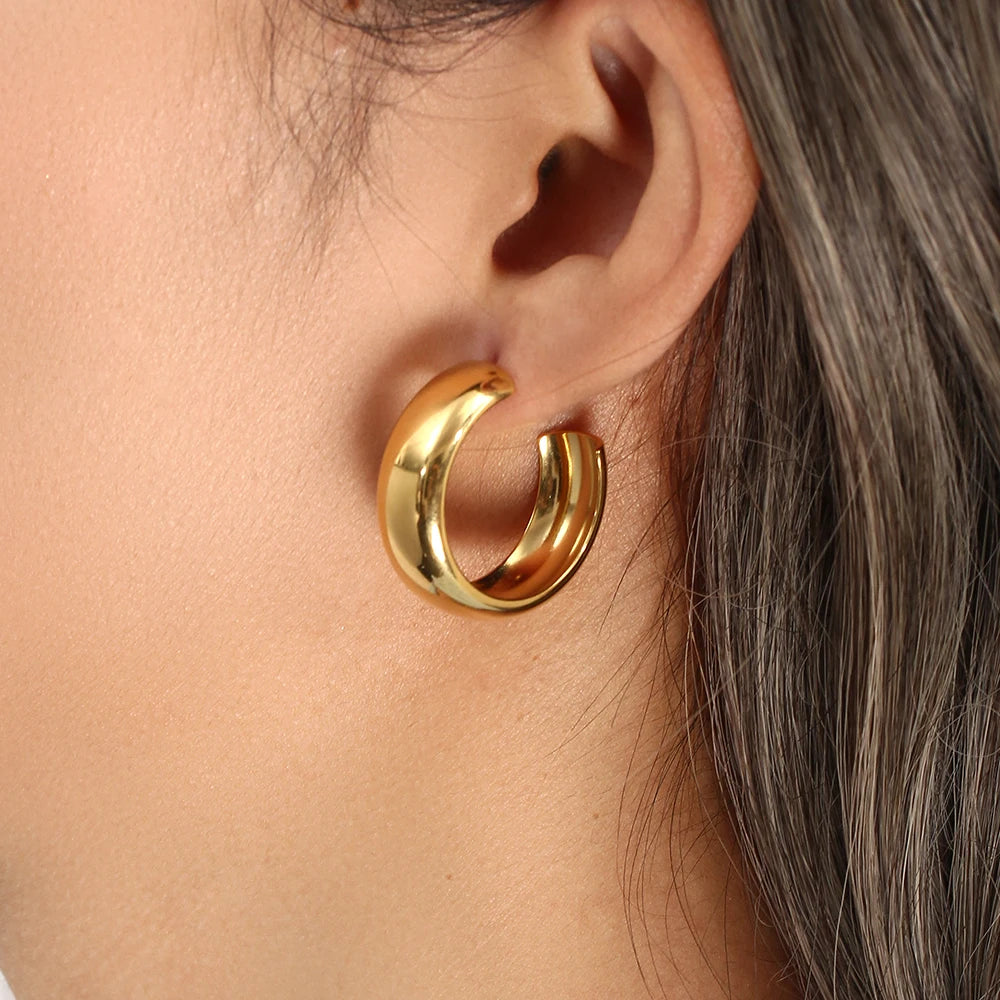 Gold hoop earring worn by a person with brown hair.