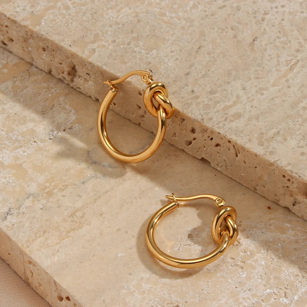 Gold hoop earrings on a textured stone surface