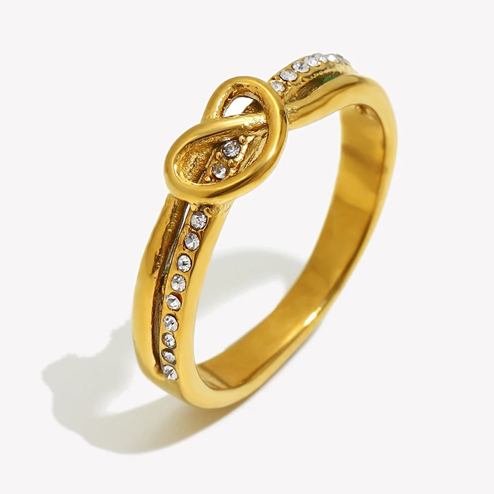 Gold ring with intricate design and small diamonds on a white background