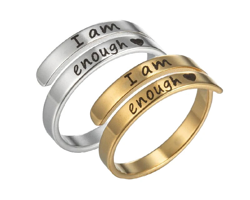 Two rings, one silver and one gold, with 'I am enough' engraving on a white background.