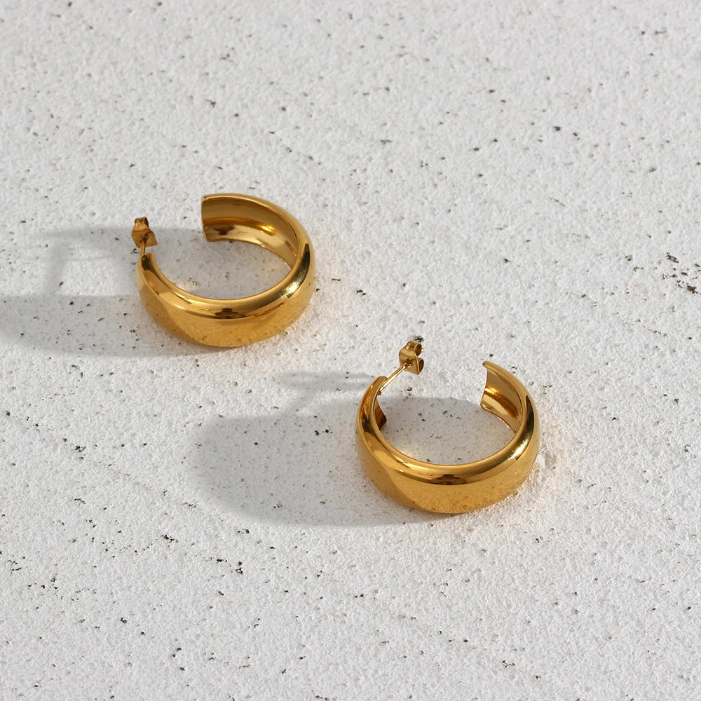 Pair of gold hoop earrings on a textured white surface