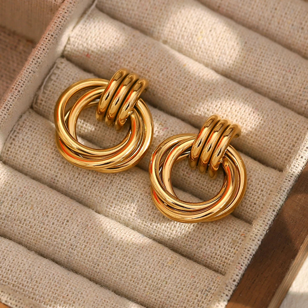 Pair of gold hoop earrings on a textured beige surface