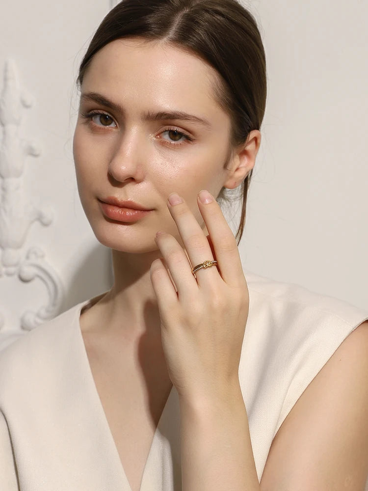Woman wearing a gold ring on her finger against a neutral background