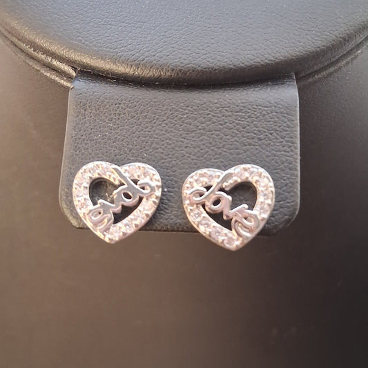 Heart-shaped earrings on a gray stand with a blurred background
